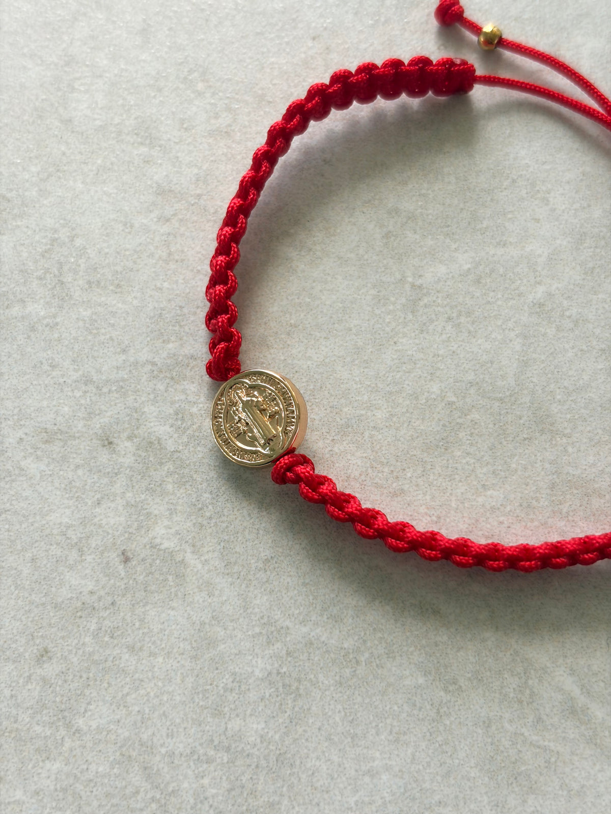 Pulsera San Benito dorada en hilo rojo